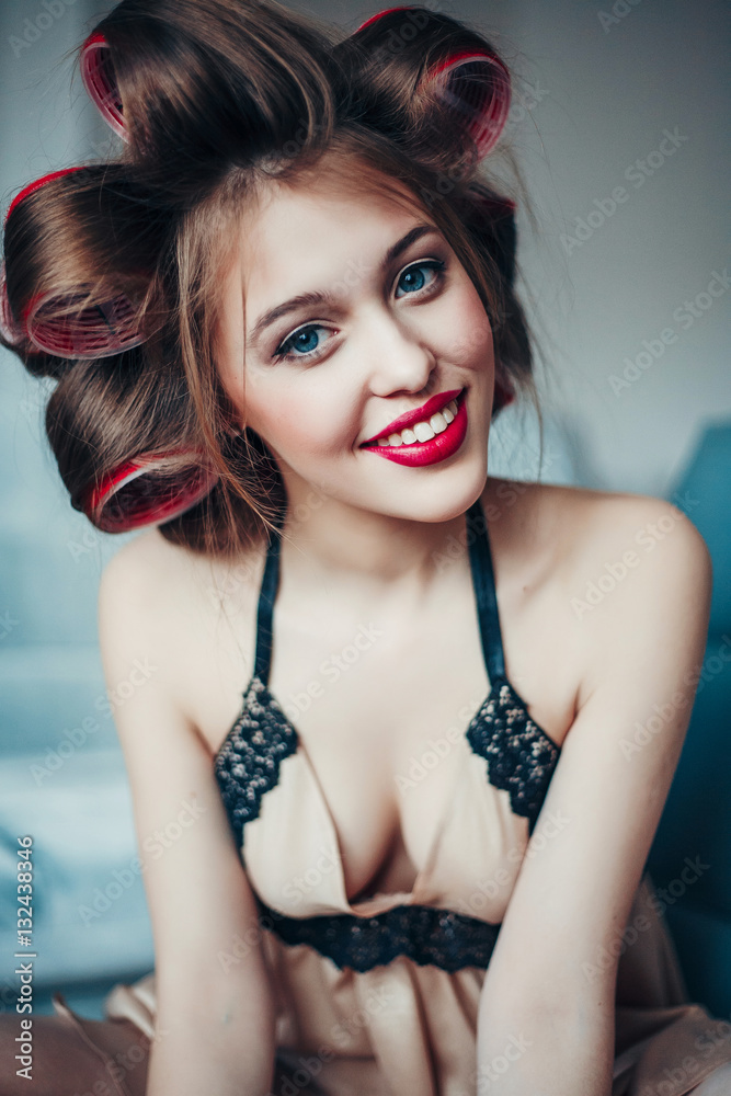 Beauty portrait of young woman wearing curlers and vintage lingerie. Photos  | Adobe Stock