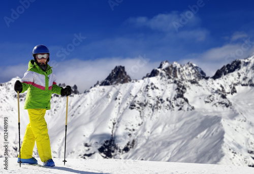 Young skier with ski poles in snow mountains at sun winter day