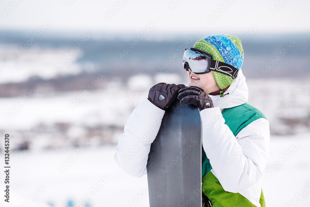 Young man standng on the snow with snowboard