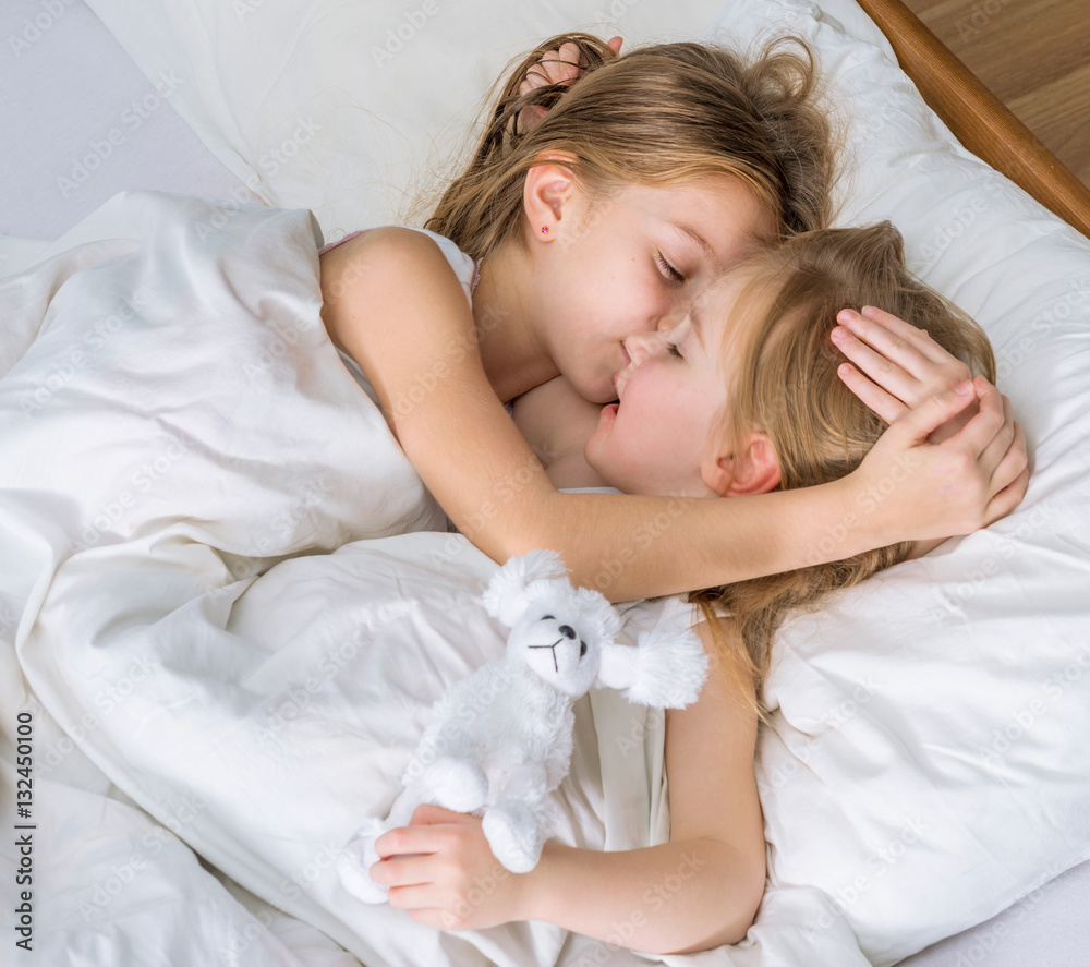 two little sisters hugging in bed two little sisters hugging in bed