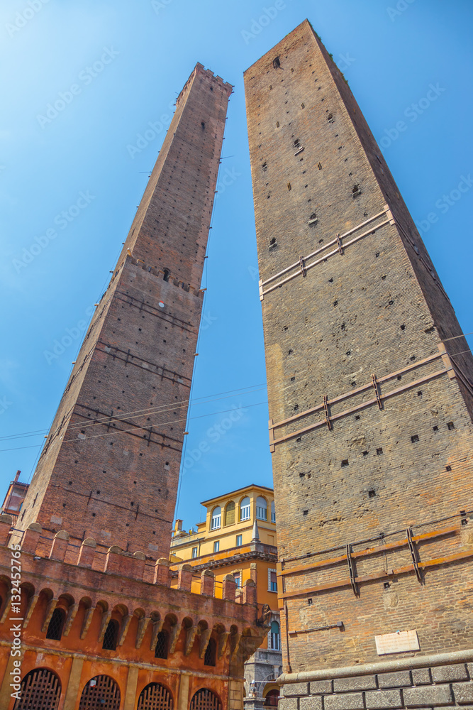 Perspective ground view of Due Torri, symbol of city under blue sky in Bologna, Piazza di Porta Ravegnana, Italy. Torre degli Asinelli and Torre Garisenda in historic center of the city.