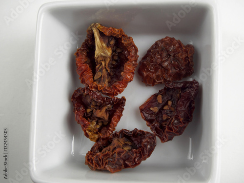 Sundried tomatoes in container on white backgroundo photo