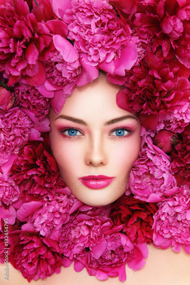 Portrait of beautiful blue-eyed woman with hot pink peonies around her face