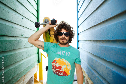 Portrait of a young guy with beard and  a long board skateboard
