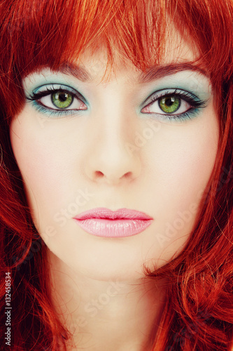 Vintage style close-up portrait of young beautiful green-eyed girl with red hair and stylish makeup