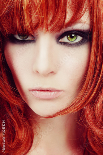 Vintage style close-up portrait of young beautiful red-haired green-eyed girl with smoky eyes make-up