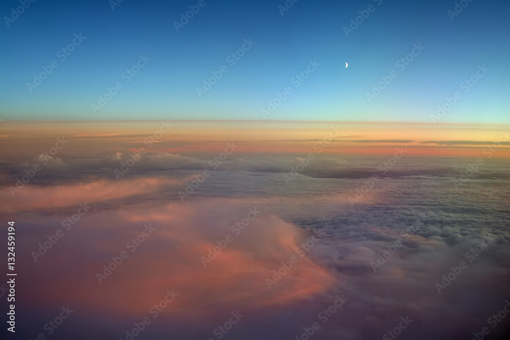 Aerial view of a cloudy sunset while flying above the clouds