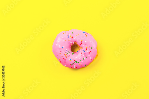 Pink round donut on yellow background. Flat lay, top view.