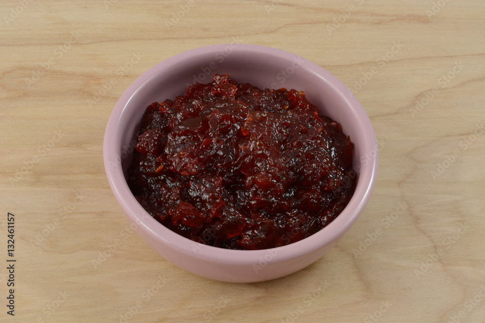 Pepper jam in pink condiment dish on wooden table Pepper jam in pink condiment dish on wooden table