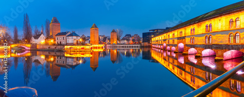 Panorama of medieval towers, bridges Ponts Couverts and Barrage Vauban with mirror reflections in Petite France during twilight blue hour, Strasbourg, Alsace, France