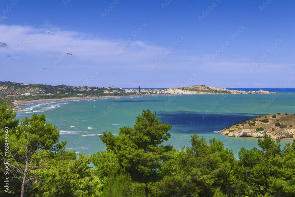Summertime relax.The most beautiful coasts of Italy: bay of Vieste.-(Apulia, Gargano) -In the foreground the Gattarella islet and in the background Castello or Scialara beach and the town of Vieste.