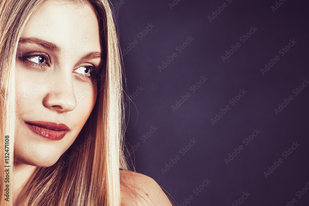 Naklejka premium Beautiful young blonde woman with long straight hair on a dark background 