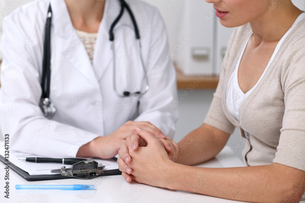 Close up of a doctor reassuring her female patient while sitting at the desk. Medicine, help and health care concept Close up of a doctor reassuring her female patient while sitting at the desk. Medicine, help and health care concept