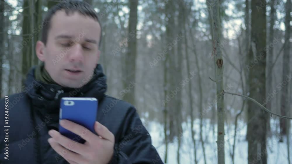 The young man goes in the winter forest and is oriented over the phone. He is looking for the right direction on the electronic map. The young man goes in the winter forest and is oriented over the phone. He is looking for the right direction on the electronic map.