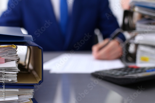 Binders with papers are waiting to be processed with businessman and secretary back in blur. Accounting planning budget, audit, insurance  and business concept © rogerphoto