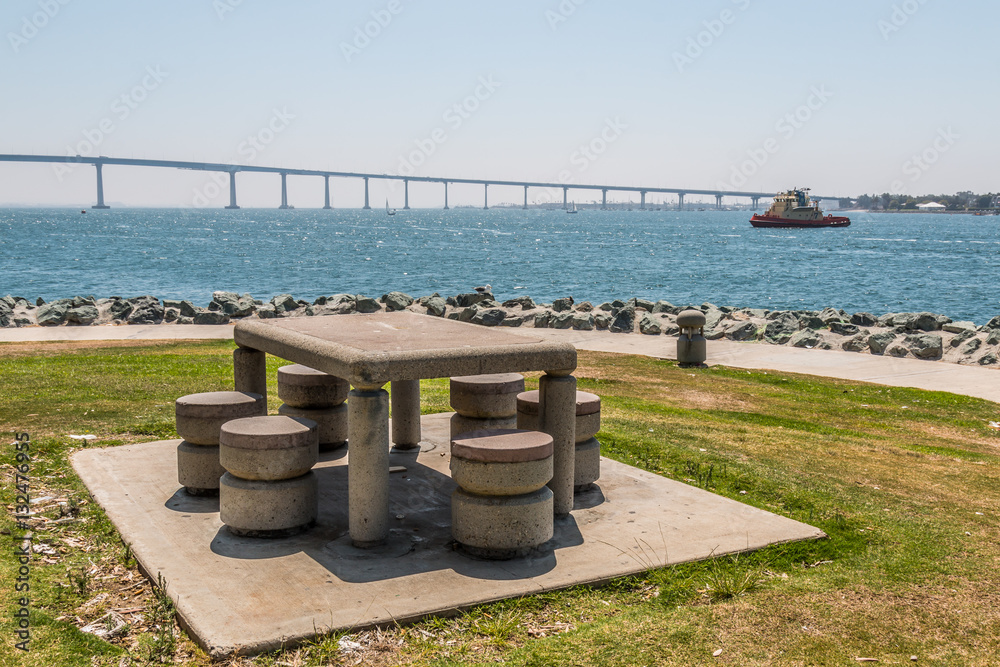 Picnic table and chairs at Embarcadero Park South in San Diego, California with Coronado Bridge in the background.