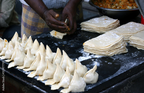 Indian Street vendor preparing or making popular Samosas filling with vegetarian ingredients in the rolled and folded rotis