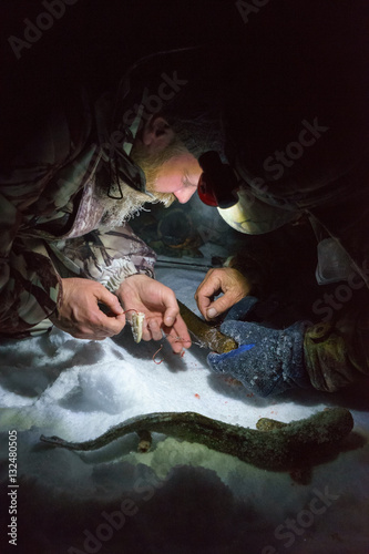 Two men is fishing at dark winter night and changing lure © Aidman