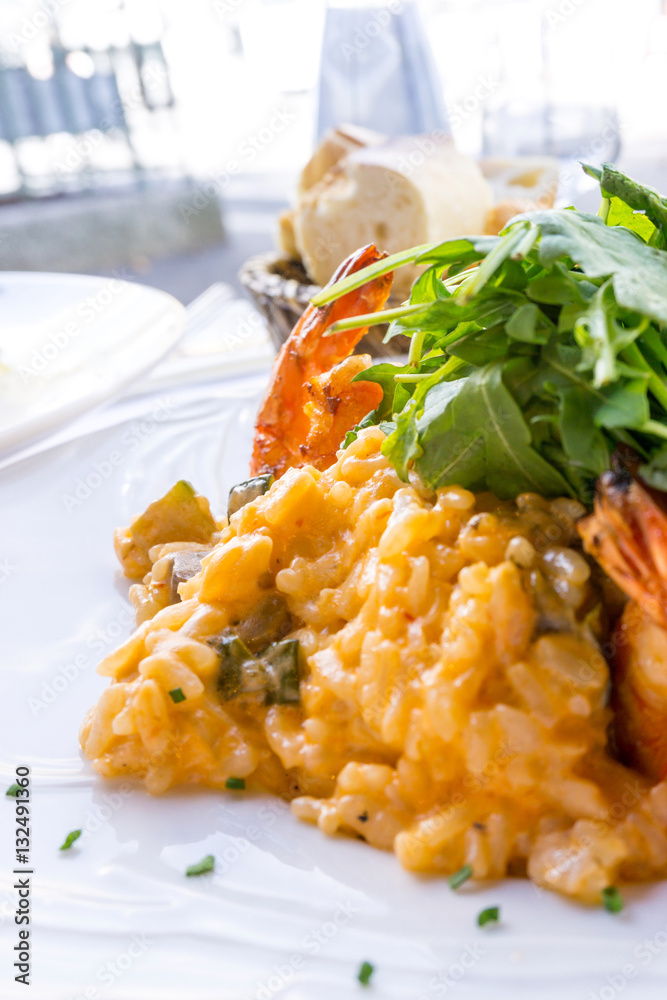 Tasty risotto with Shrimp, fresh herbs vegetables on a white pla Tasty risotto with Shrimp, fresh herbs vegetables on a white pla