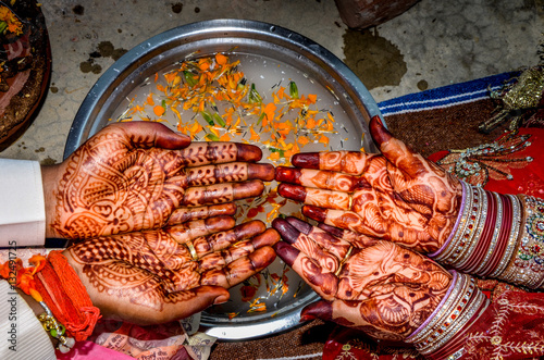 Mehndi on the hands of Hindu couple alongwith water filled plate with flowers