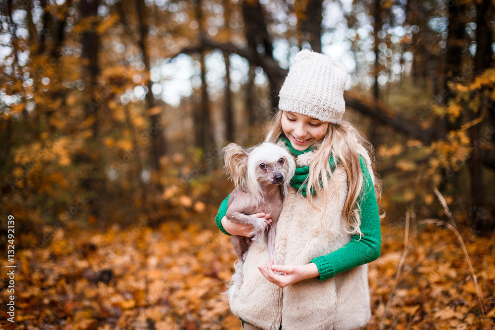 A pretty girl with a chinese crested dog outdoors in autumn