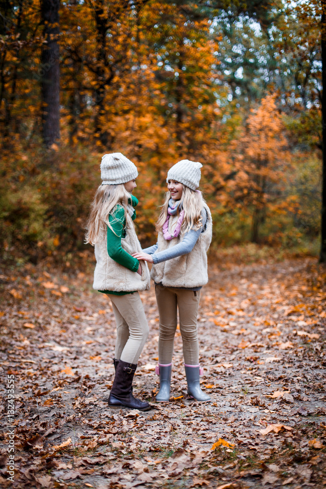 Fototapeta premium Twins sisters outdoors in the park in autumn