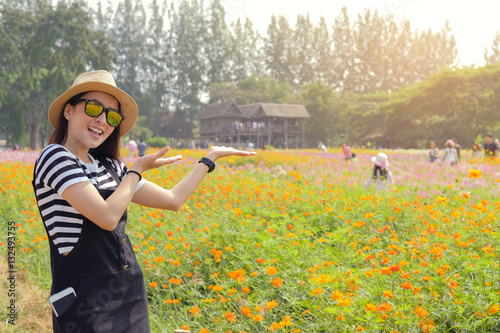 A young beautiful girl wear sunglass enjoying a sunny day in a field of flowers.