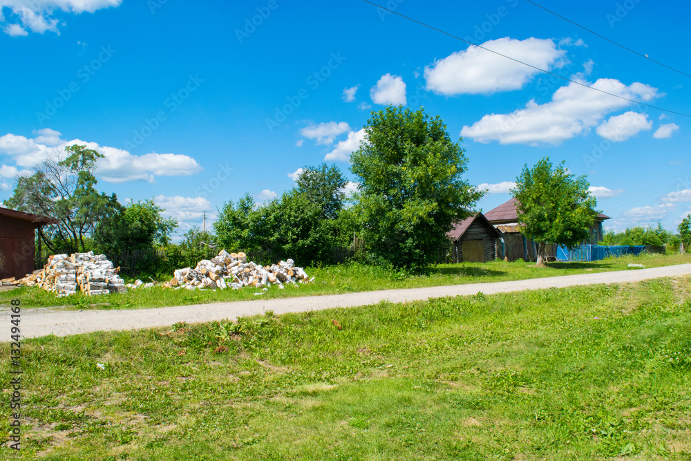 Russian village rural street with road and fuel wood