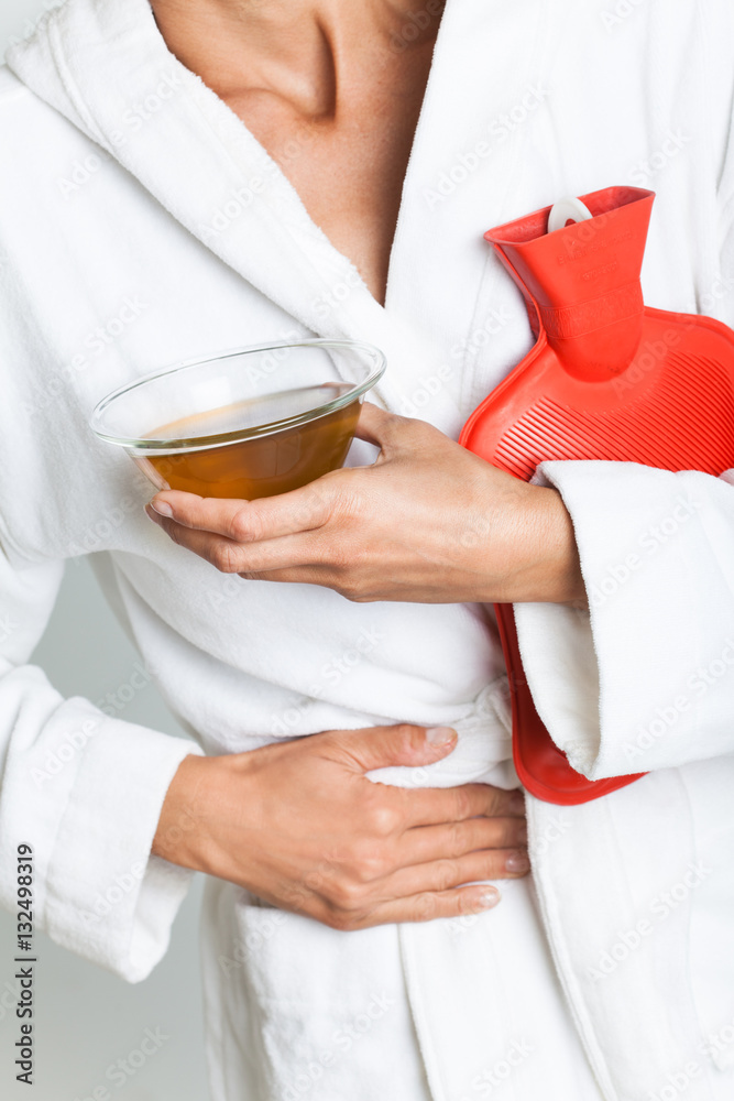 femme qui a mal au ventre avec une bouillotte Photos | Adobe Stock