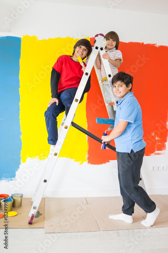 Children helping painting wall at home