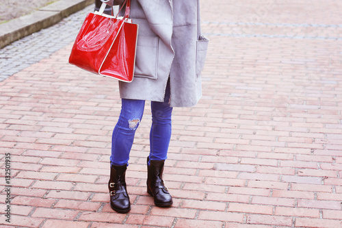 Fashionable girl in gray coat with red trendy handbag