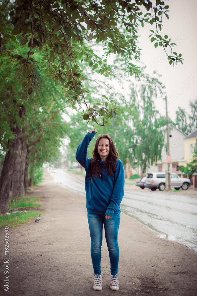 drops of a fresh rain fall on the girl from tree branch, the in blue clothes walks around the city drops of a fresh rain fall on the girl from tree branch, the in blue clothes walks around the city