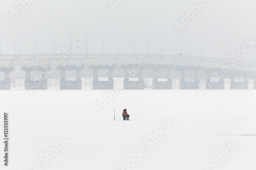 Winter fishing on the ice. The Volga river in Saratov, Russia. Road bridge on the horizon