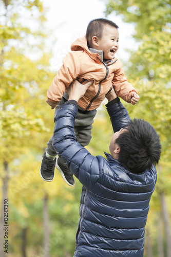 Happy real father and son playing in front of ginkgo trees