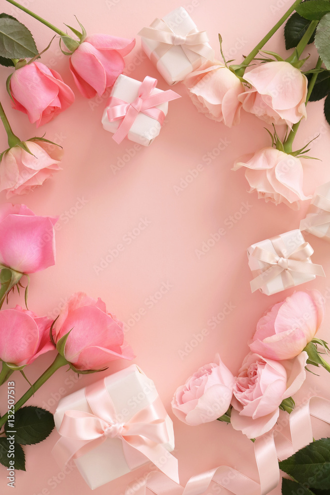 Frame of beautiful pink tone roses and gift boxes on pastel pink background,top view