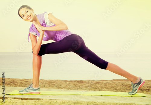 Laughing woman exercising yoga poses on beach
