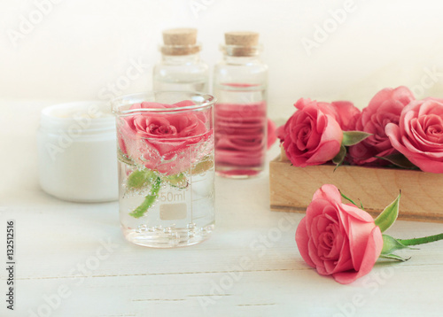 Rose scent holistic cosmetic. Fresh pink blossom, array of glass vials and apothecary bottles. Flower Aromatherapy. Soft light and focus. 