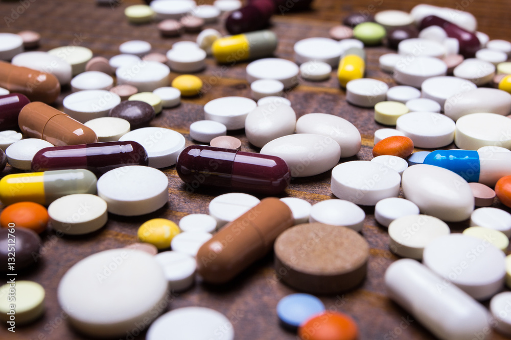 Many different colorful medication and pills on a background of brown wooden table Many different colorful medication and pills on a background of brown wooden table