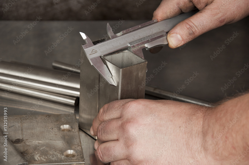 The man measured a piece of stainless steel with a caliper The man measured a piece of stainless steel with a caliper