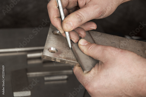 Man`s hands with metal stylus pointing out on a piece of metal