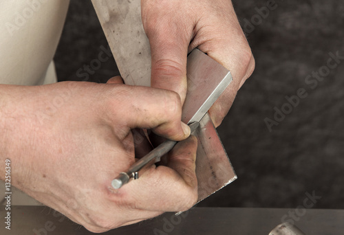 Bild auf Leinwand Man`s hands with metal stylus pointing out on a piece of metal