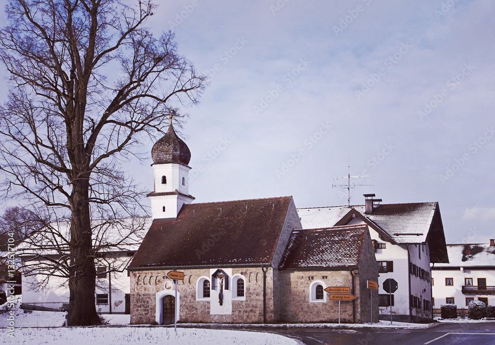Bavarian winter landscape with snow, crossroad and ancient chapel with onion dome