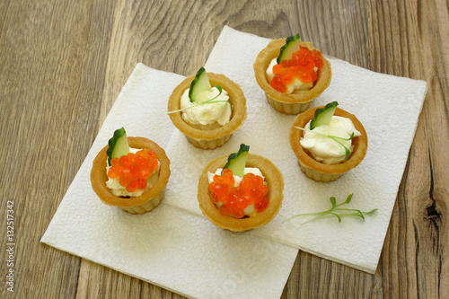 tartlets with red caviar and soft cheese on a wood background