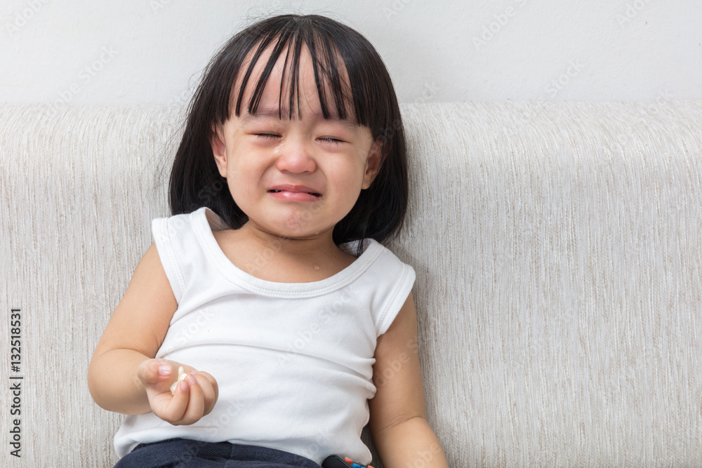 Asian Chinese little girl sitting on the sofa crying Asian Chinese little girl sitting on the sofa crying