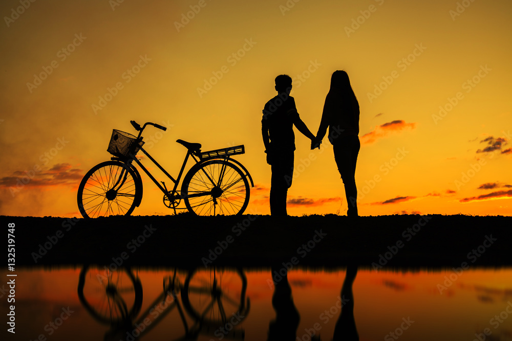 Silhouette of sweet couple in love happy time and bicycle in bea Silhouette of sweet couple in love happy time and bicycle in bea