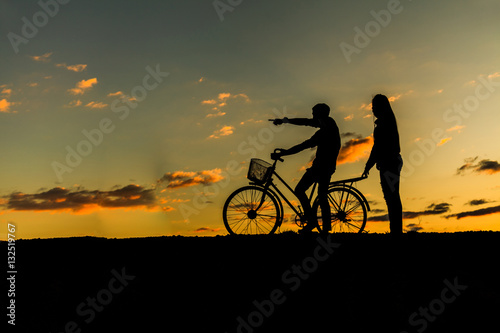 Silhouette of sweet couple in love happy time and bicycle in bea