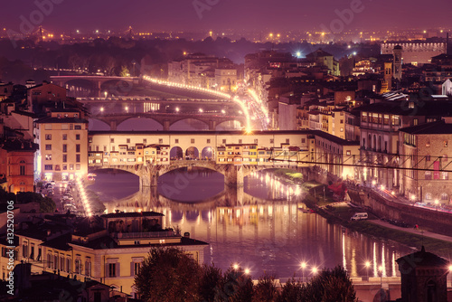 Night view of Florence city with Ponte Vecchio over river Arno and illumination. Travel sightseeing background.