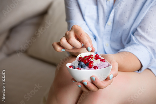 Closeup of woman's hands holding cup with organic yogurt with blueberries, coconut and fresh mint. Homemade vanilla yogurt in girl's hands. Breakfast, snack. Healthy eating and lifestyle concept