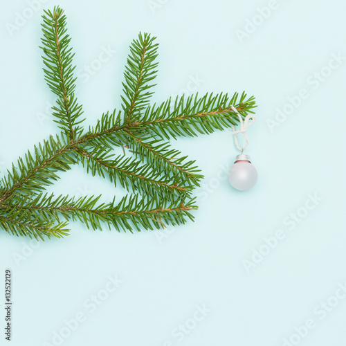 Top view on Christmas tree branch with nice round decoration on blue background. Holiday  season concept. Merry Cgristmas