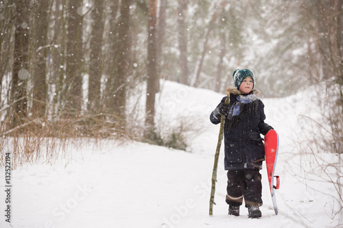 Cute kid boy walking in the forest in a winter day. Child having fun outdoors. Winter and Christmas concept